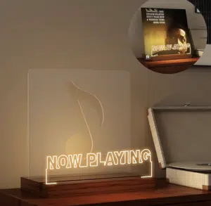 An illuminated "Now Playing" sign with a clef symbol sits on a shelf next to a vinyl record player, perfect as gift ideas for musicians. A smaller inset shows the sign alongside a record album.